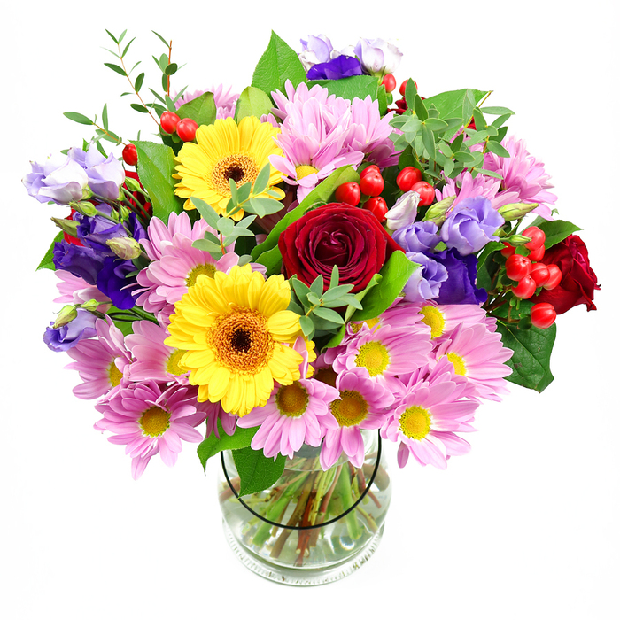 A bright and abundant floral arrangement stands tall in a clear glass vase, its colours glowing vividly against a white background that keeps every detail crisp. At the core of this bouquet are lush red roses, their velvety petals spiralling tightly towards the centre, giving a sense of depth and heartfelt emotion. Just in front, two sunny yellow gerbera daisies hold their faces open, each with a rich brown-orange centre that draws the eye and adds a cheerful, contemporary note, much like the friendly buzz of Ickenham's local cafés. Surrounding these focal flowers is a generous collar of pink and lavender daisies or chrysanthemums, their many fine petals and bright yellow centres creating a soft, lively texture that makes the arrangement feel full and welcoming. Rising through this pastel cushion, stems of lisianthus in deep purple and soft lilac add height and gentle movement, their bell-shaped blooms giving the design an air of quiet sophistication, reminiscent of the calm paths through Swakeleys Park. Tiny clusters of glossy red hypericum berries are tucked between the blooms, adding rounded, jewel-like accents and an extra layer of texture. The bouquet is richly dressed with greenery: broad, deep green leaves anchor the composition and frame the flowers, while lighter green sprigs and shoots give it a freshly picked, garden-inspired look. Through the transparent vase, the neatly trimmed stems fan out into clear water, a subtle sign of professional conditioning and care. Crafted in Ickenham with an eye for balance and colour harmony, this bouquet feels ideal for marking milestones-birthdays, anniversaries, exam results-or simply adding a radiant, uplifting presence to a hallway, dining table, or cosy living room.