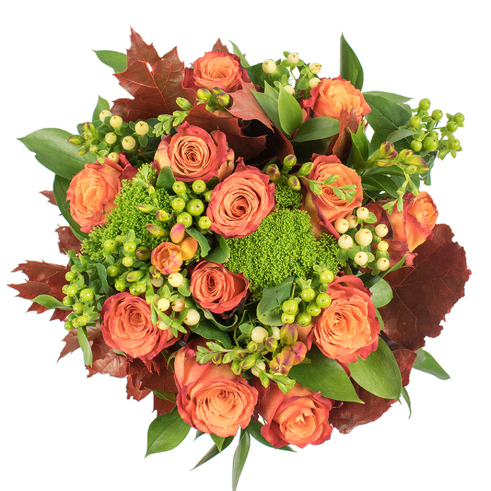 This top-down portrait of an autumn bouquet presents a carefully balanced composition that celebrates texture as much as colour. Heavily packed in a circular form, the arrangement is dominated by fully open roses whose petals graduate from a soft, warm orange at the centre through coral-peach tones to outer edges blushed with russet and reddish-brown, mirroring the subtle shifts of leaves on a blustery November day. Nestled between the large blooms are dense clusters of hypericum berries in contrasting shades: bright, almost lime green against creamy, pale-yellow berries that create delicate focal points across the surface. Small mounds of green 'trick' dianthus - plush, moss-like and vividly green - provide a playful, tactile counterpoint to the roses' smooth velvet, adding architectural interest while softening the silhouette. The florist's eye has introduced deep russet, oak-shaped leaves and broad glossy foliage to anchor the palette; these darker elements form visual punctuation and reinforce a harvest sensibility, as if the bouquet had been gathered from a neighbourhood green at dusk. Light from above warms the petals' interiors and casts gentle shadows that convey density and abundance. The scent profile suggested is subtle: a mix of rose fragrance and earthy, mossy notes. Handcrafted with purpose, this arrangement sits naturally as a Thanksgiving centrepiece, an autumnal gift, or a comforting accent for a living room, bringing together the tactile richness and seasonal colour that celebrates the turning of the year in and around Ickenham.