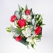 A hand-tied bouquet rests as if just set down on a kitchen table in Ickenham, glowing with the warmth of an early spring morning. At its heart, velvety red roses unfurl in full, confident blooms, their rich crimson colour deepened by soft natural light. Around them, pink-red carnations ripple with ruffled, almost feathery petals, adding movement and texture to the cluster of flowers. Snow-white chrysanthemums and tiny daisy-like blooms create a bright halo, their rounded heads and neatly layered petals suggesting innocence and joy. Threads of delicate gypsophila weave between the larger flowers like a gentle mist, softening every edge and giving the bouquet a light, airy feel. Cool eucalyptus stems arc outward, their silvery green leaves introducing a modern note, while deeper tropical foliage anchors the design with glossy, sculpted shapes. Seen from above, the bouquet feels perfectly balanced-neither rigid nor wild-just the right mix of structure and spontaneity, as if shaped by an experienced local florist who knows how people in Ickenham like their flowers to feel: welcoming, generous, and quietly elegant. You can almost imagine this arrangement being carried down Swakeleys Road to brighten a doorstep, or set in a favourite vase to celebrate a birthday, a homecoming, or a simple thinking of you. The colours suggest affection and delight, while the combination of soft petals, crisp greenery, and airy filler flowers evokes the sensation of holding a fresh breeze in your hands. It is a bouquet made to mark moments, to lift moods, and to add a lovingly crafted burst of colour to everyday life in this corner of West London.